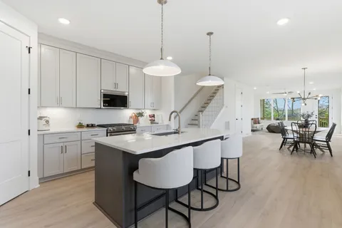 a kitchen with stainless steel appliances kitchen island granite countertop a table chairs sink and cabinets