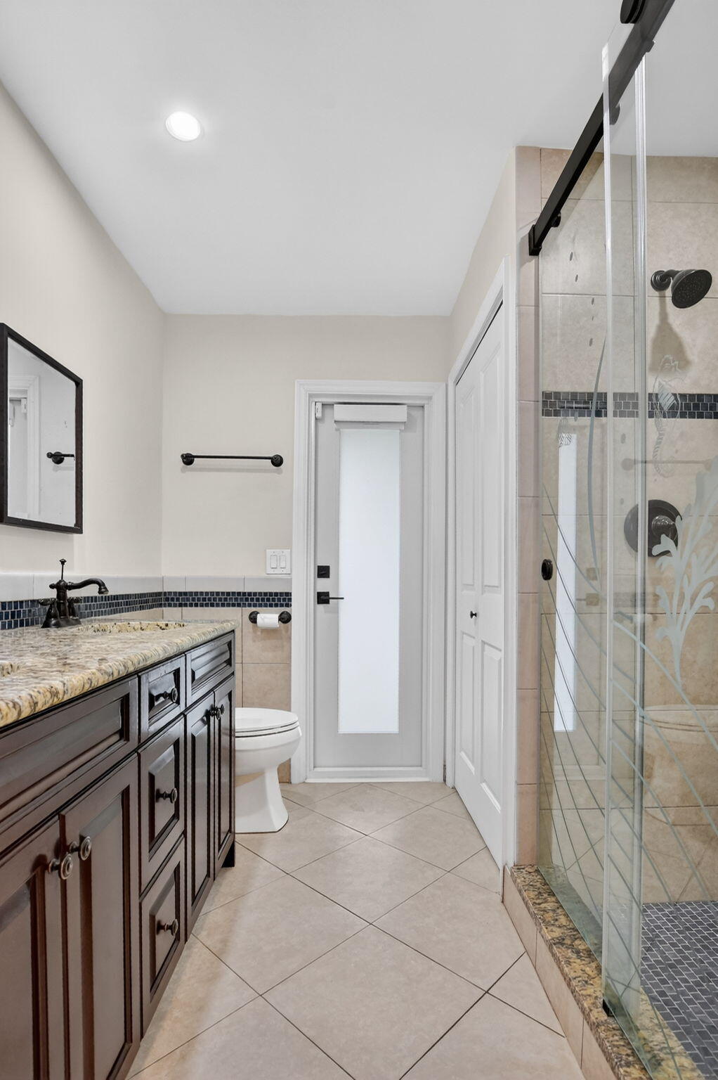 10194 Canoe Brook Circle Boca Raton, FL 33498 - Photo 25 of 42 a bathroom with a granite countertop sink a toilet a glass door shower and a mirror