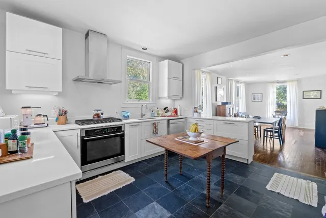a kitchen with stainless steel appliances kitchen island granite countertop a table chairs sink and cabinets