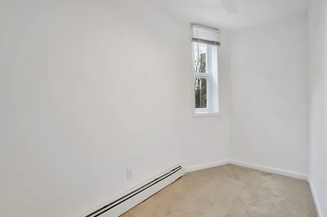 an empty room with a ceiling fan and carpet