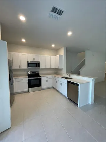 a large white kitchen with stainless steel appliances granite countertop a stove and a sink cabinets