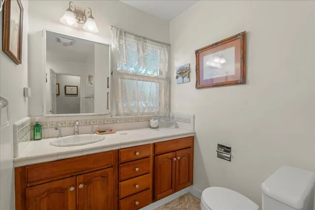 a bathroom with a granite countertop sink mirror and toilet