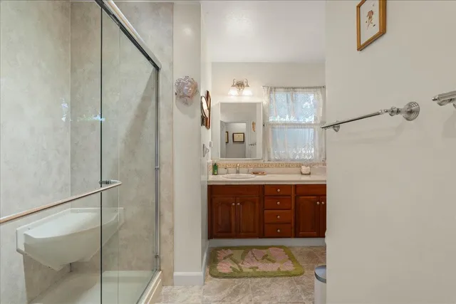 a bathroom with a granite countertop sink a mirror and shower