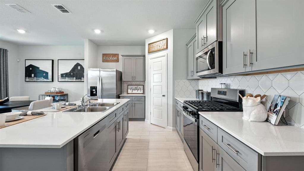 557 Pendleton Avenue Keene, TX 76059 - Photo 3 of 32 a kitchen with stainless steel appliances granite countertop a sink stove oven and white cabinets with wooden floor