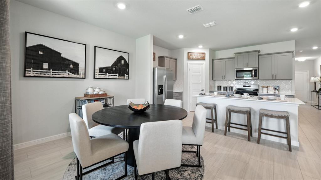 557 Pendleton Avenue Keene, TX 76059 - Photo 5 of 32 a kitchen with stainless steel appliances kitchen island granite countertop a dining table chairs and a refrigerator