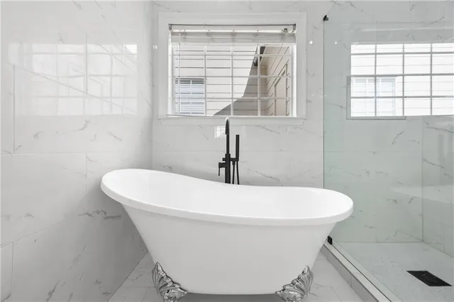 a white bath tub sitting in a bathroom next to a window