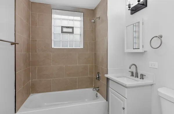 a bathroom with a granite countertop sink a toilet and shower
