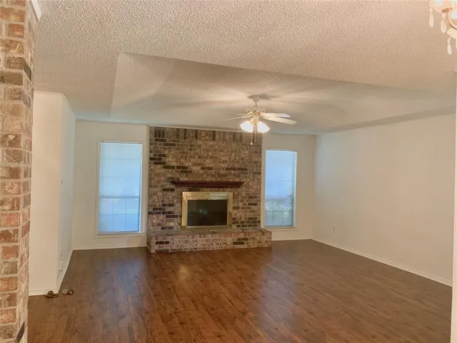 an empty room with wooden floor fireplace and staircase