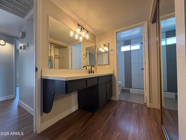 a room with a sink a mirror and wooden floor