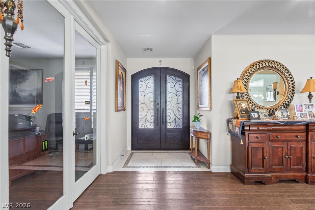 8431 Durango Ranch Court Las Vegas, NV 89113 - Photo 5 of 49 The inviting entryway features a detailed arched door and warm wooden flooring.