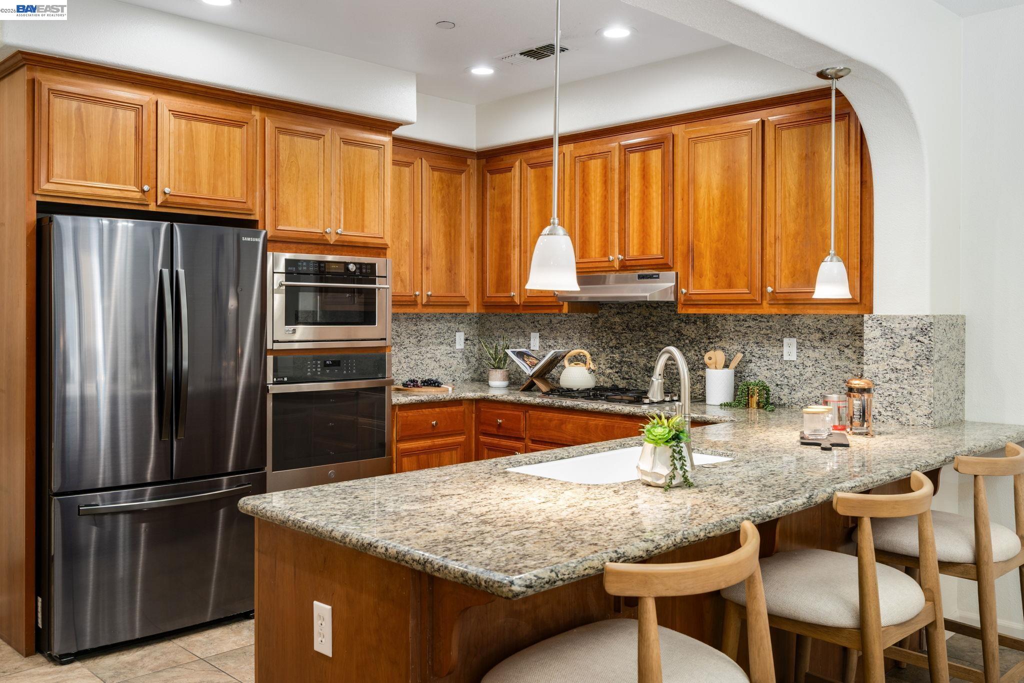 4653 Rimini Court Dublin, CA 94568 - Photo 14 of 44 a kitchen with granite countertop a refrigerator a stove a sink dishwasher and wooden cabinets with wooden floor