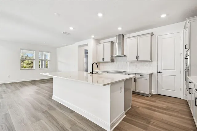 a large kitchen with stainless steel appliances granite countertop a sink a stove a refrigerator and white cabinets with wooden floor