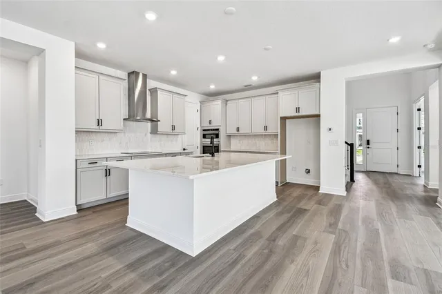 a large kitchen with stainless steel appliances granite countertop a lot of counter space and wooden floor
