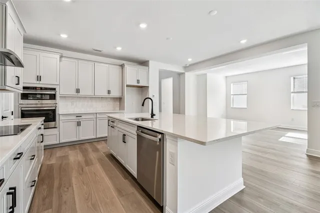 a kitchen with stainless steel appliances a sink cabinets and wooden floor