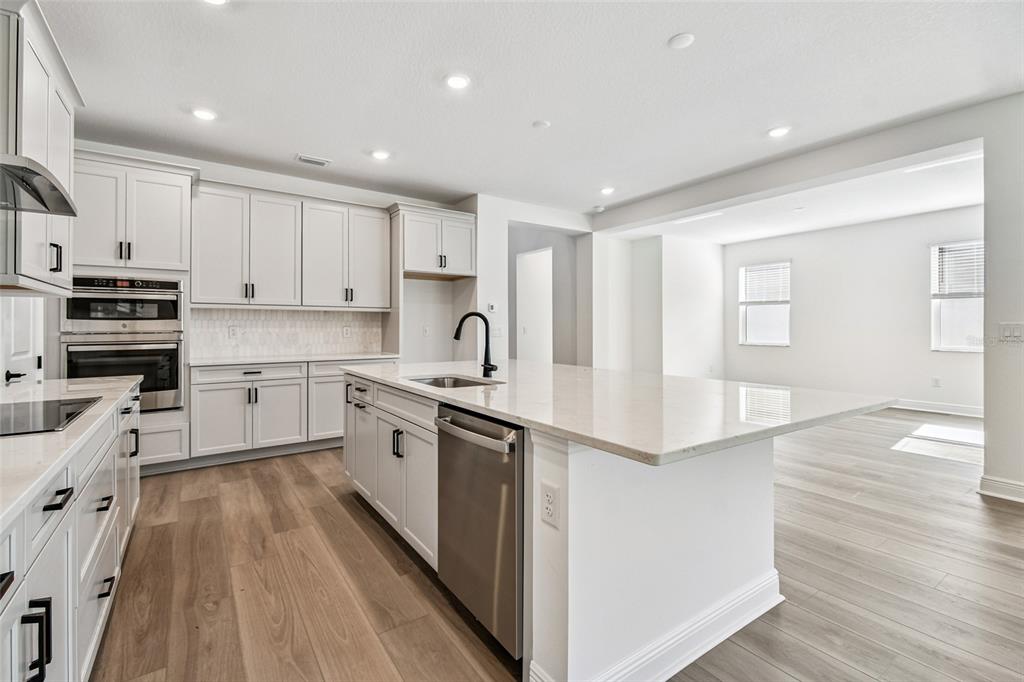 3677 142nd Terrace Parrish, FL 34219 - Photo 10 of 93 a large kitchen with stainless steel appliances granite countertop a lot of counter space and wooden floor