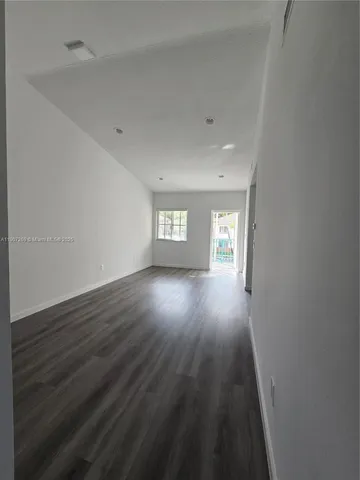 a view of empty room with window and wooden floor