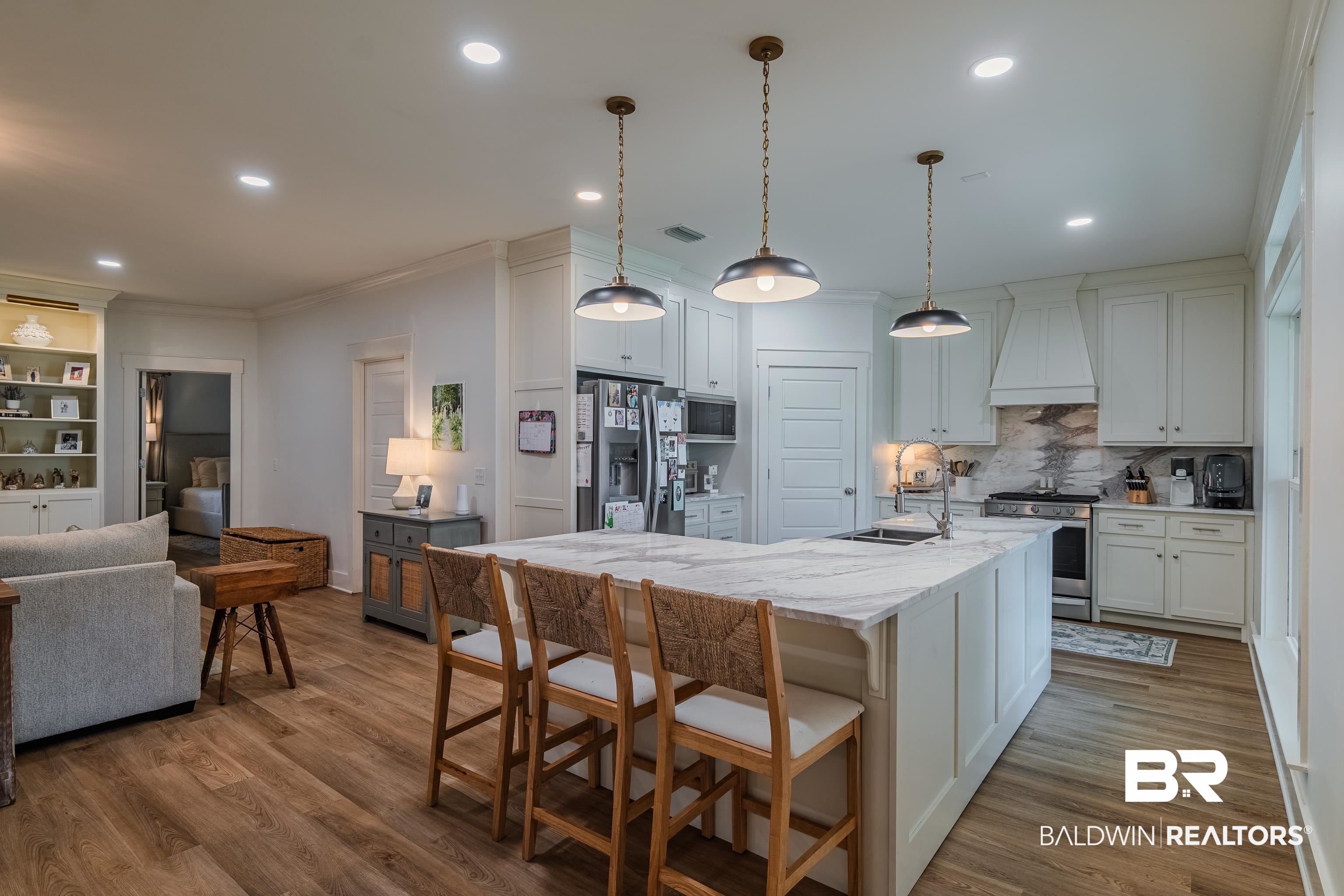 19121 Boothe Road Fairhope, AL 36532 - Photo 12 of 41 Kitchen with a breakfast bar area, light stone countertops, stainless steel appliances, an island with sink, and white cabinets