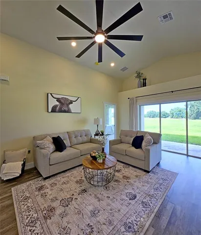 a living room with furniture and a large window with wooden floor