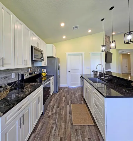 a large kitchen with granite countertop a lot of counter space and stainless steel appliances