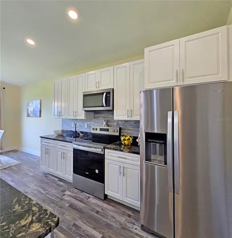 a kitchen with granite countertop a refrigerator stove and microwave