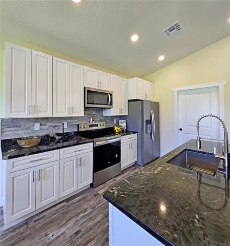 a kitchen with kitchen island granite countertop a stove sink and cabinets