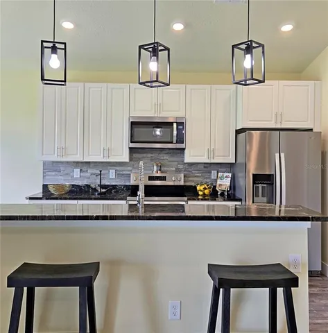 a kitchen with stainless steel appliances granite countertop a sink refrigerator and microwave