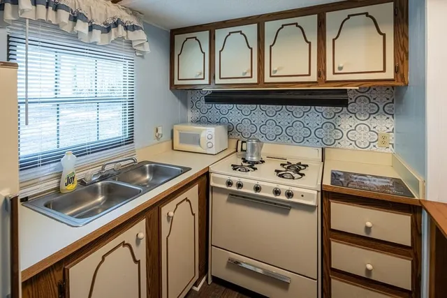 a kitchen with granite countertop a sink stove and cabinets