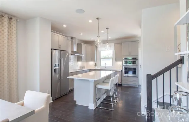 a kitchen with stainless steel appliances refrigerator dining table and chairs