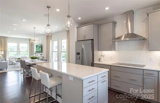 a large kitchen with cabinets chairs and wooden floor