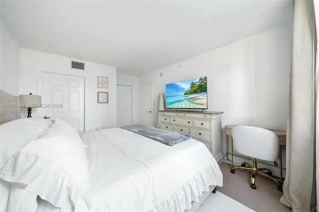 a bedroom with a bed and a flat tv screen on the dresser