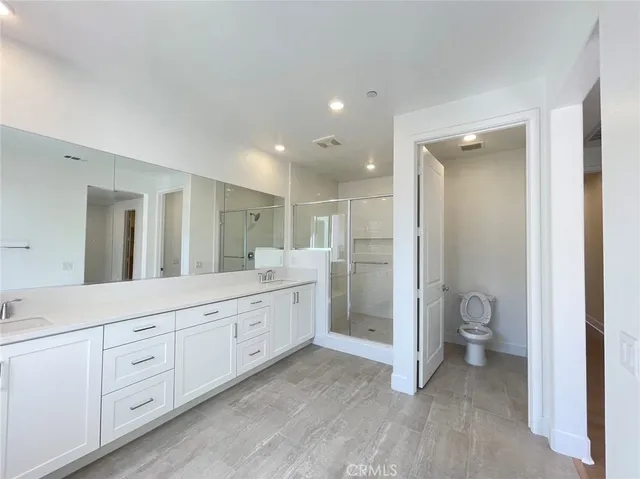 a spacious bathroom with a granite countertop sink a toilet and a mirror