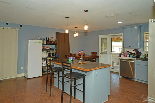 a kitchen with stainless steel appliances a dining table chairs stove and refrigerator