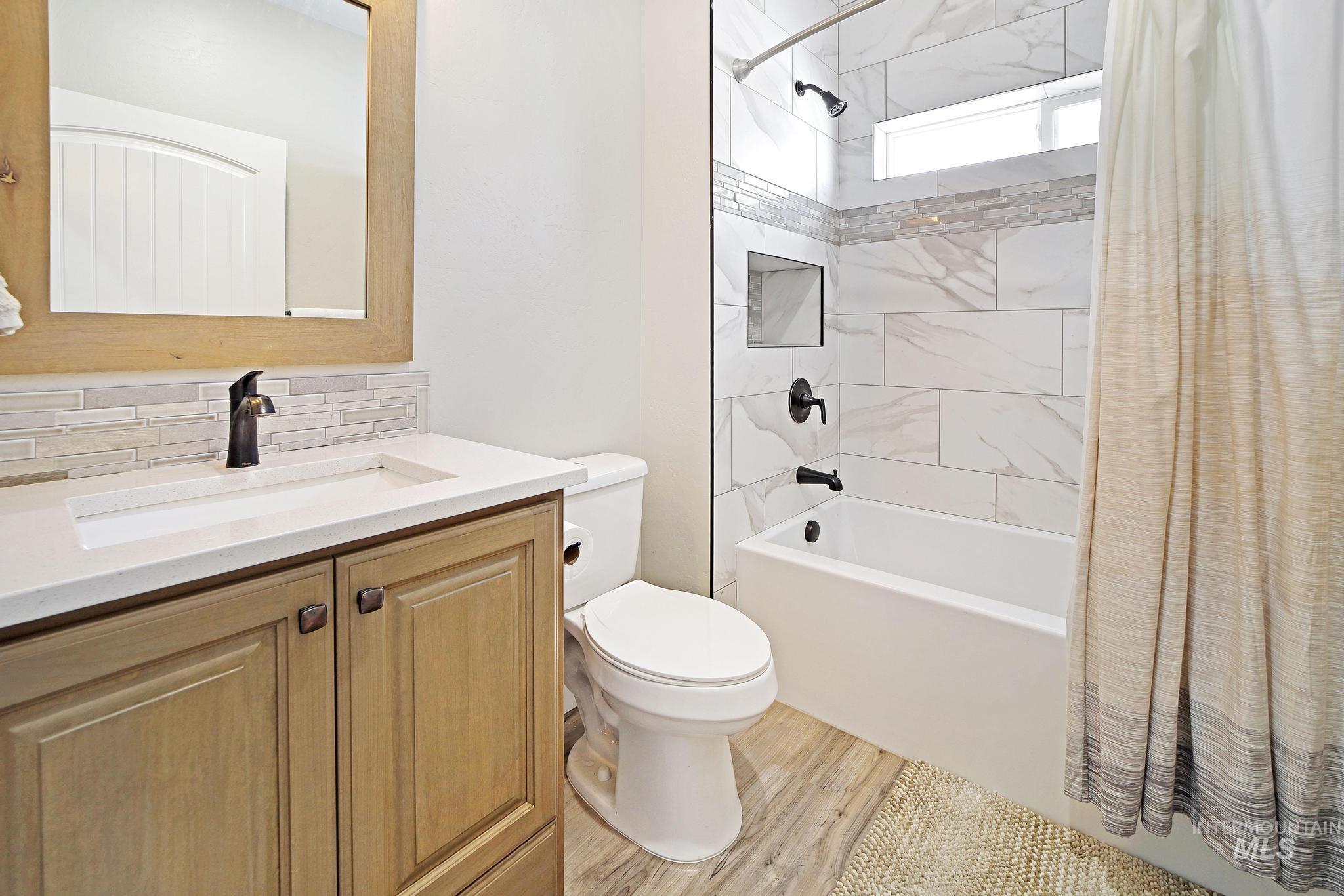 284 Sandi Road Twin Falls, ID 83301 - Photo 12 of 22 Full bathroom featuring shower / bathtub combination with curtain, vanity, light wood-type flooring, and backsplash