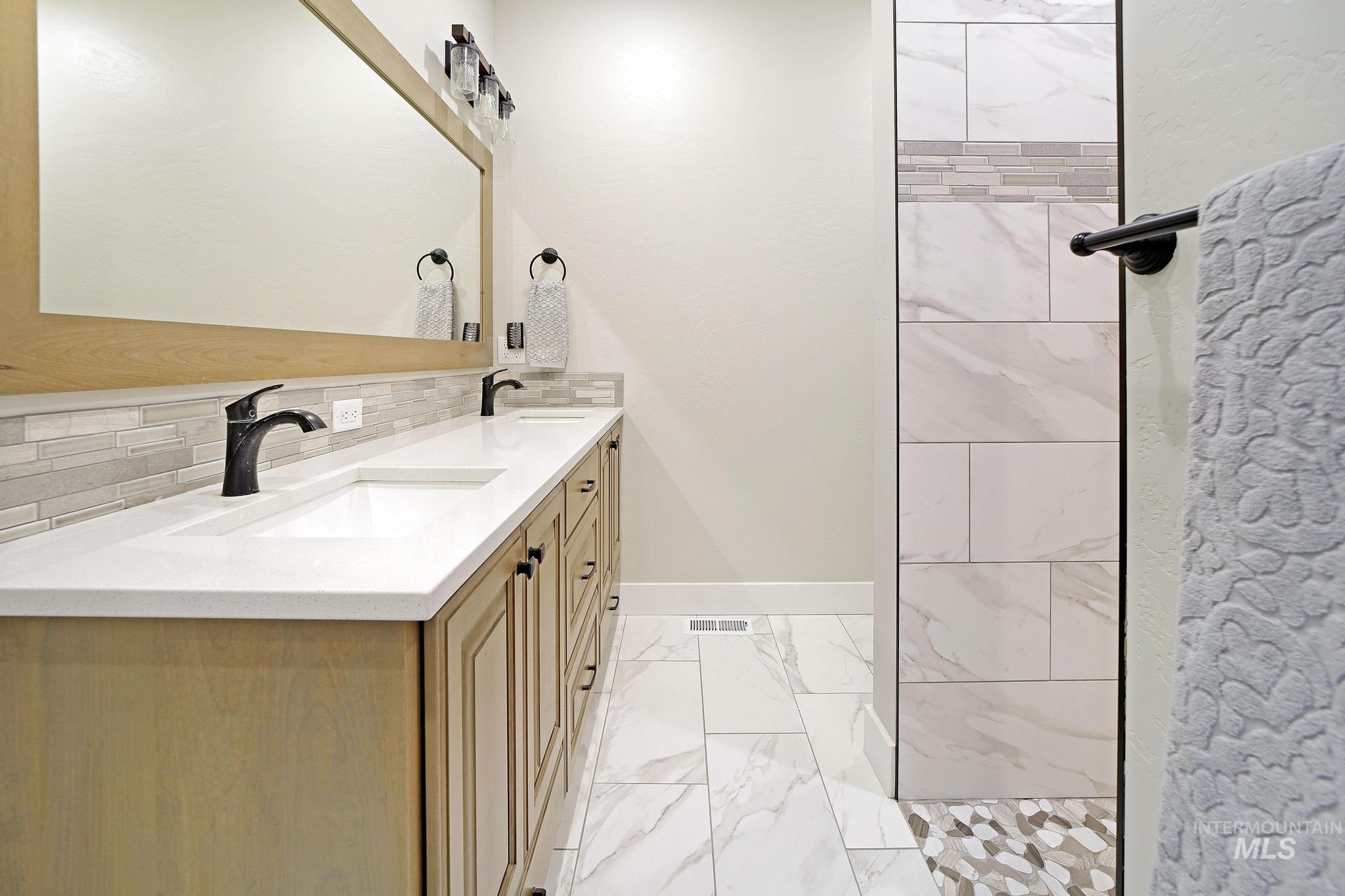 284 Sandi Road Twin Falls, ID 83301 - Photo 8 of 22 Bathroom with double vanity, backsplash, light marble finish flooring, and walk in shower