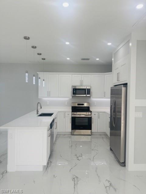 165 Patio Street Lehigh Acres, FL 33974 - Photo 19 of 34 Kitchen with stainless steel appliances, light marble finish floors, hanging light fixtures, white cabinets, and recessed lighting