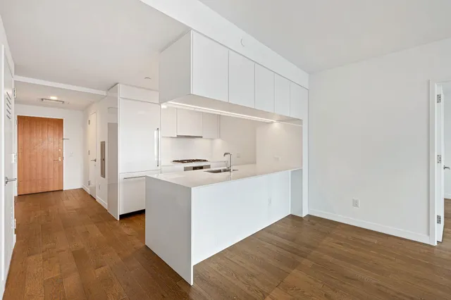 a kitchen with stainless steel appliances granite countertop a sink stove and white cabinets with wooden floor