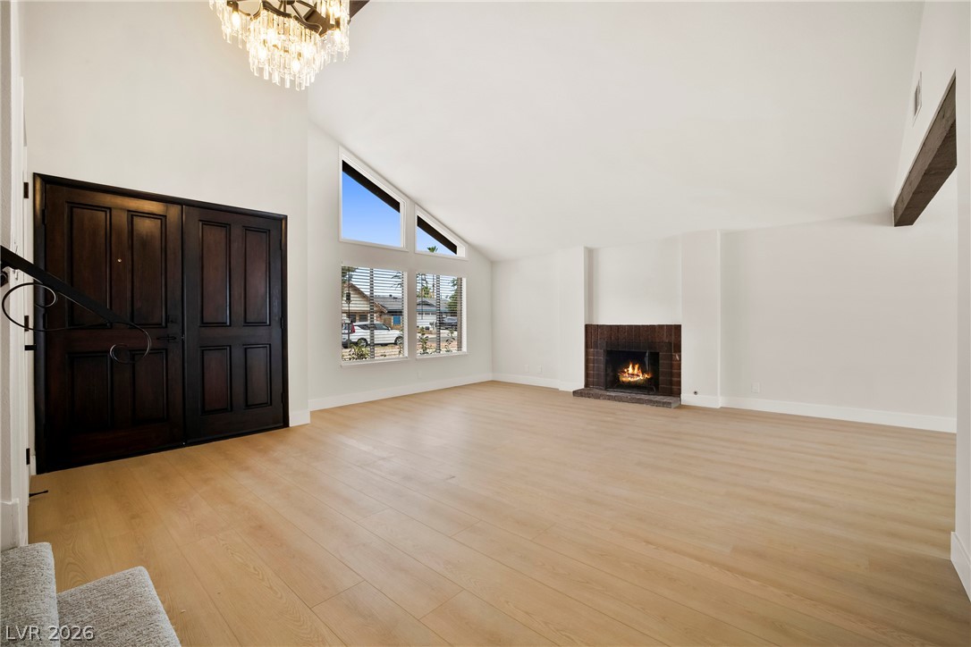 2411 Doherty Way Henderson, NV 89014 - Photo 2 of 34 Enter into an airy living space with vaulted ceilings, light-hued hardwood flooring, and a warm brick fireplace.
