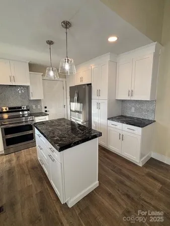 a kitchen with stainless steel appliances granite countertop a stove a sink and a refrigerator