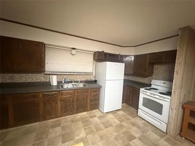 a kitchen with granite countertop a refrigerator and a stove top oven