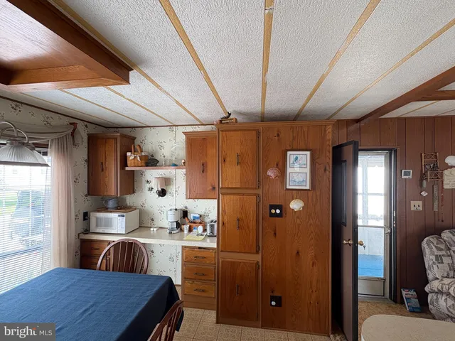 a kitchen with stainless steel appliances granite countertop a refrigerator a sink dishwasher a dining table and chairs with wooden floor