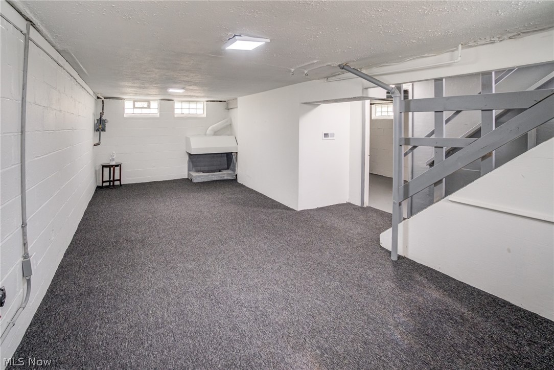 4383 Wyatt Road Cleveland, OH 44128 - Photo 20 of 33 Spacious lower-level room featuring gray carpeting, painted block walls, and an integrated fireplace structure