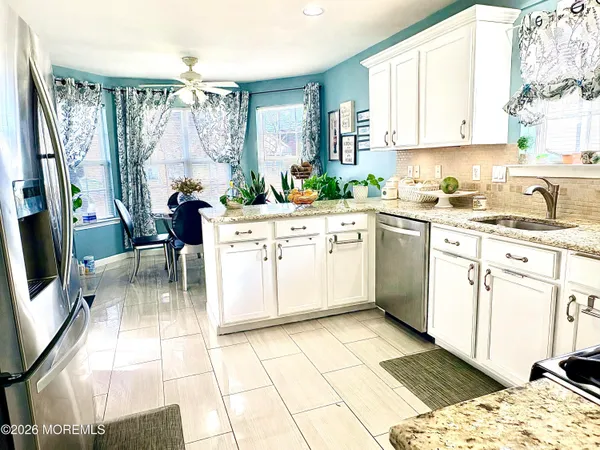 a kitchen with stainless steel appliances granite countertop a refrigerator a stove a sink a counter space and a couch