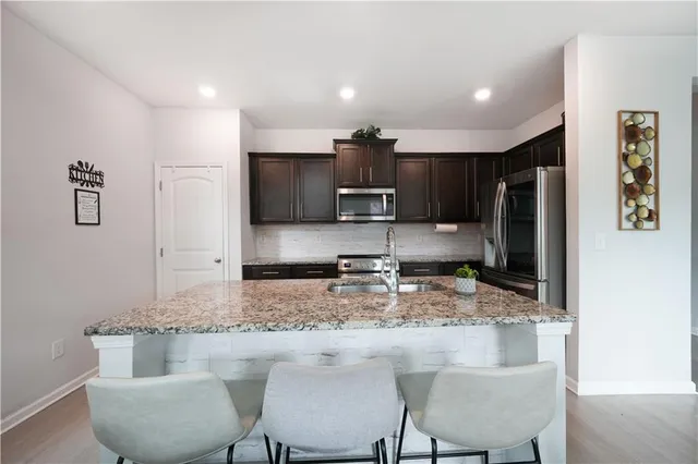 a kitchen with kitchen island granite countertop a refrigerator and microwave