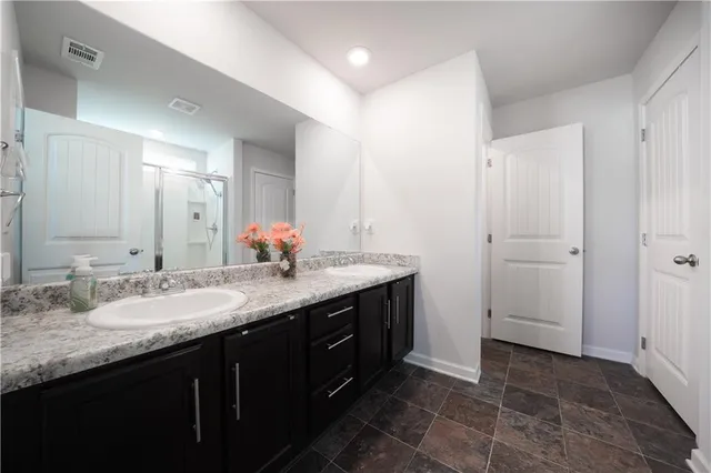 a bathroom with a granite countertop double vanity sink and a mirror