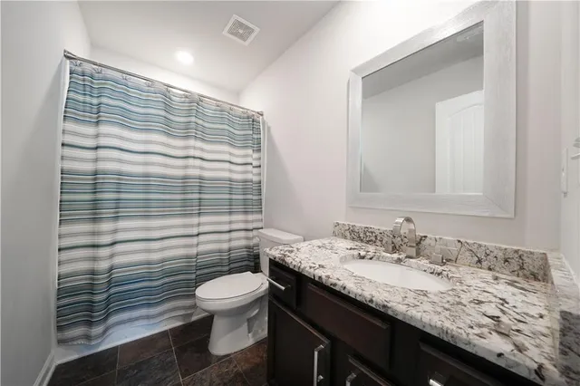 a bathroom with a granite countertop sink toilet a mirror and shower