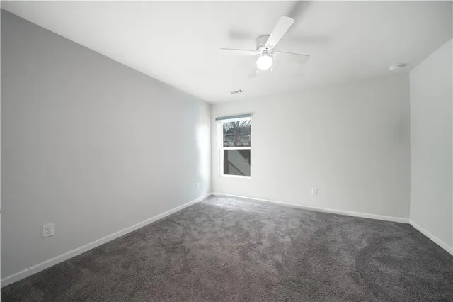 an empty room with a window and chandelier fan