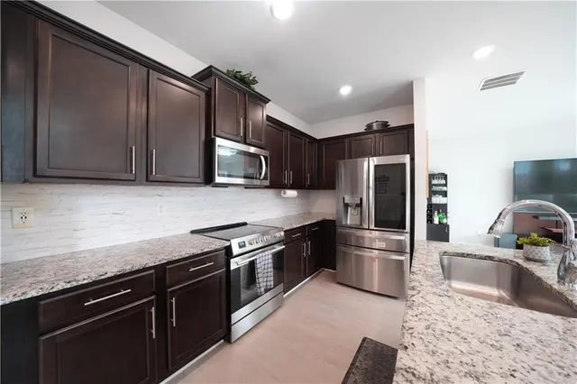 a kitchen with stainless steel appliances granite countertop a sink stove and refrigerator