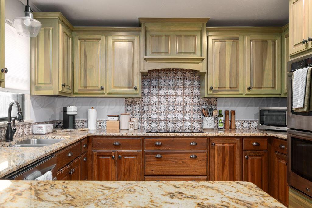 4314 Emil Avenue Amarillo, TX 79106 - Photo 15 of 44 a kitchen with granite countertop wooden cabinets stainless steel appliances a sink and a window