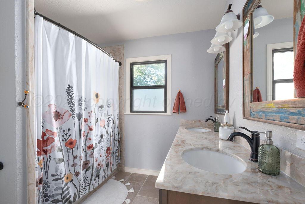 4314 Emil Avenue Amarillo, TX 79106 - Photo 36 of 44 a bathroom with a granite countertop sink a mirror and shower curtain