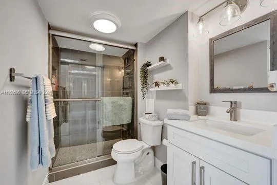 a bathroom with a shower sink vanity mirror and toilet